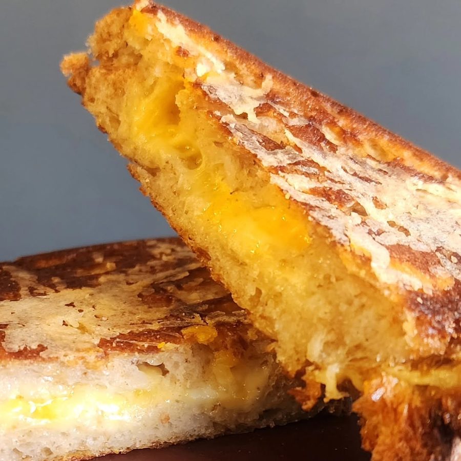 A toastie cut in half, showing melted cheddar inside golden toasted bread